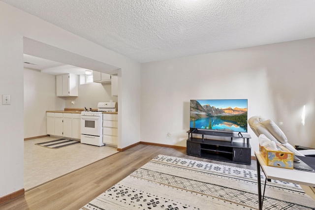 living area featuring a textured ceiling, baseboards, and light wood-type flooring