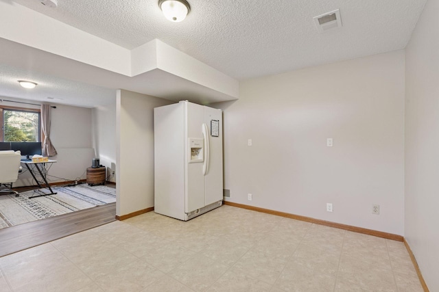 empty room with baseboards, a textured ceiling, and visible vents