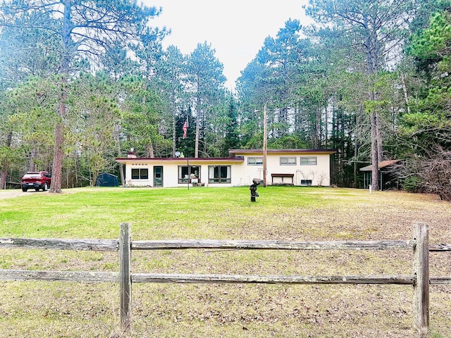 view of front of home featuring stucco siding, fence, and a front lawn