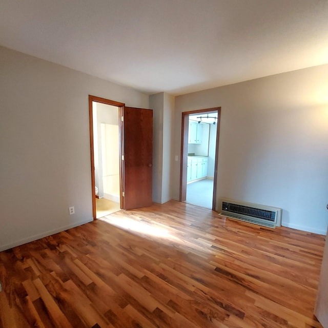 unfurnished room featuring baseboards, wood finished floors, and visible vents