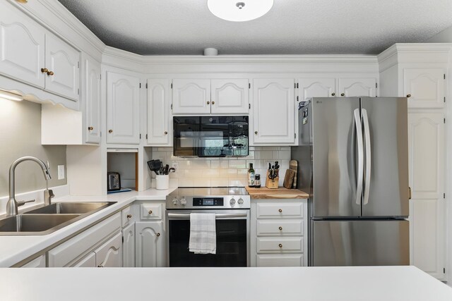 kitchen with backsplash, a sink, light countertops, stainless steel appliances, and white cabinetry