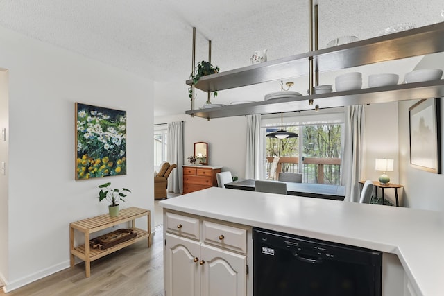 kitchen with light wood-type flooring, open shelves, dishwasher, and light countertops