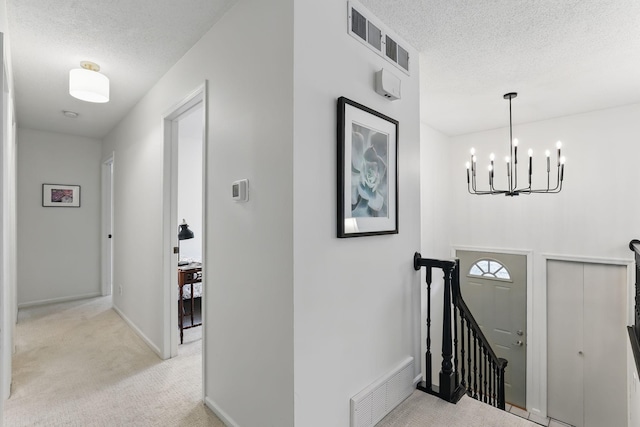 foyer entrance featuring light carpet, a textured ceiling, and visible vents