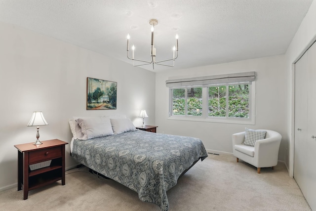 bedroom with light colored carpet, an inviting chandelier, a textured ceiling, baseboards, and visible vents