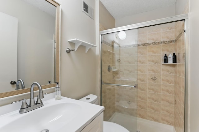 full bathroom featuring vanity, toilet, a textured ceiling, a shower stall, and visible vents