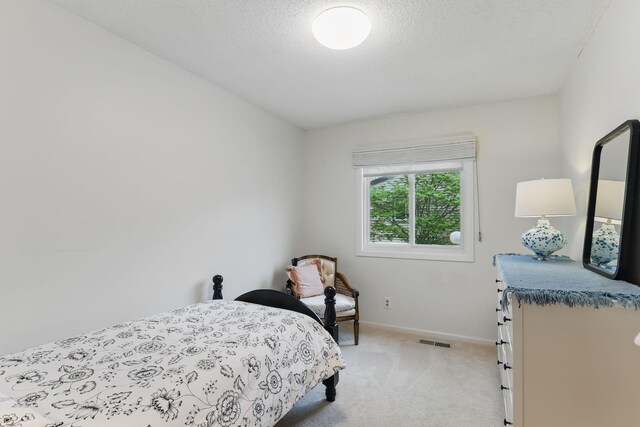 bedroom with light colored carpet, baseboards, visible vents, and a textured ceiling