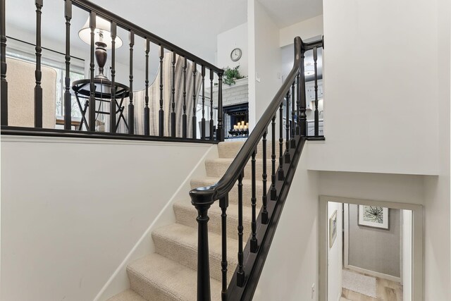 staircase with a brick fireplace and a towering ceiling