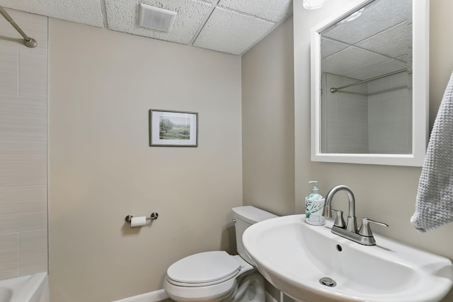 bathroom featuring a paneled ceiling, visible vents, a sink, baseboards, and toilet