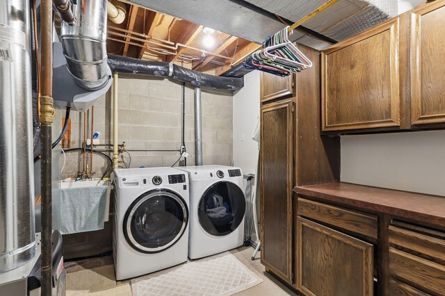 laundry room with concrete block wall, a sink, cabinet space, and washer and clothes dryer
