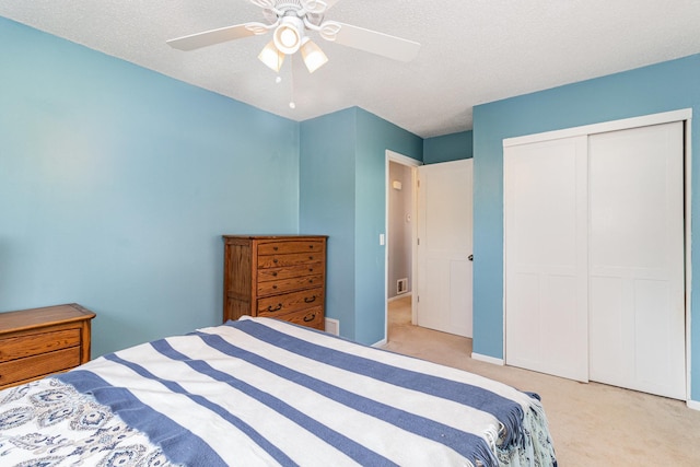 bedroom with carpet flooring, ceiling fan, a textured ceiling, visible vents, and a closet