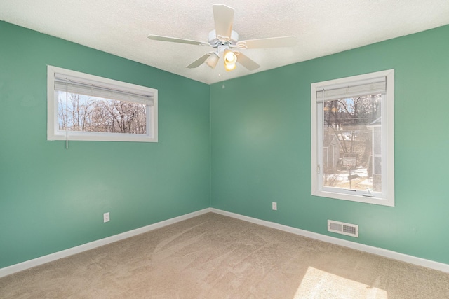 unfurnished room featuring a ceiling fan, a textured ceiling, visible vents, carpet floors, and baseboards