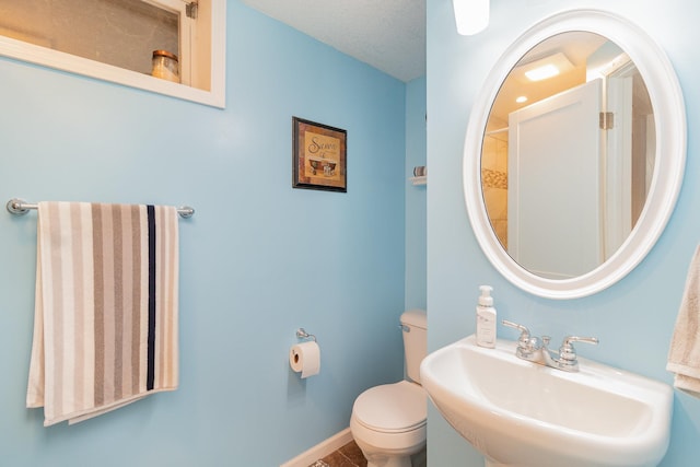 bathroom with baseboards, a sink, and toilet