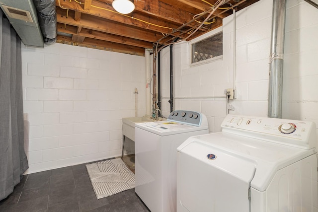 laundry room with concrete block wall, laundry area, and washer and dryer