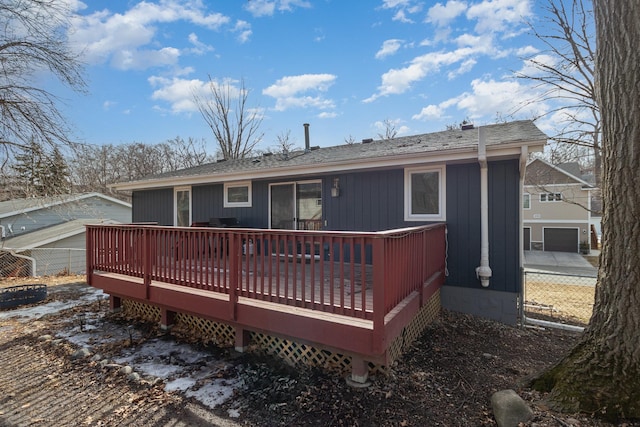 back of house with a deck, fence, and a shingled roof