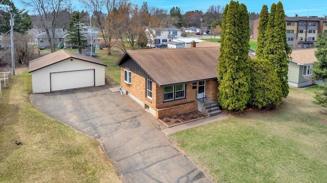 ranch-style home with an outdoor structure, a front lawn, a shingled roof, a residential view, and a detached garage