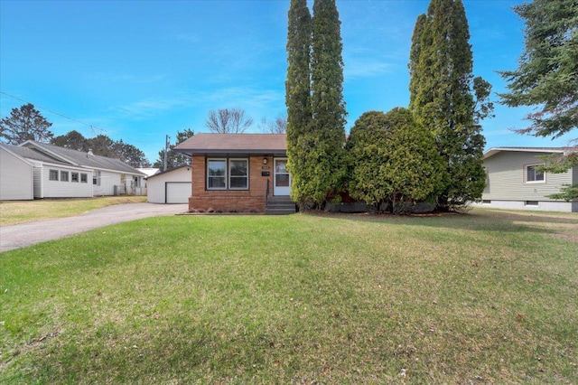 bungalow-style home with a detached garage, an outdoor structure, brick siding, and a front yard