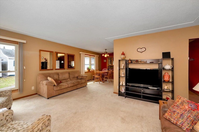 living area with baseboards, ceiling fan, and carpet