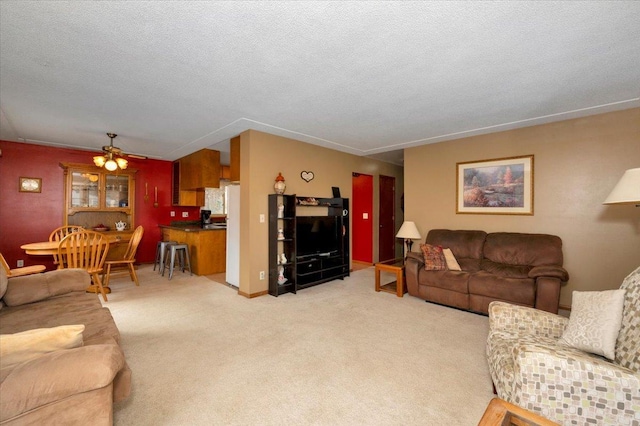 carpeted living area with a textured ceiling and ceiling fan