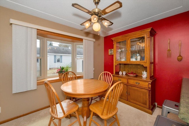 dining area with a ceiling fan, baseboards, and light carpet