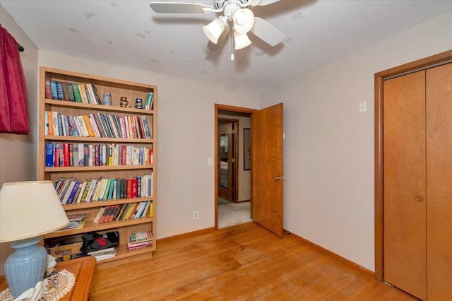 living area with baseboards, a ceiling fan, and wood finished floors