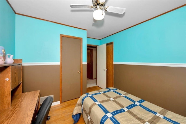 bedroom with ceiling fan, ornamental molding, and wood finished floors