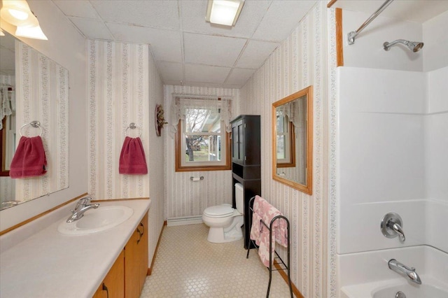 bathroom featuring vanity, toilet, wallpapered walls, baseboards, and bathing tub / shower combination