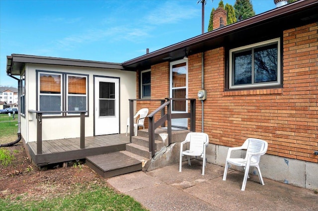 back of property with brick siding, a chimney, and a patio