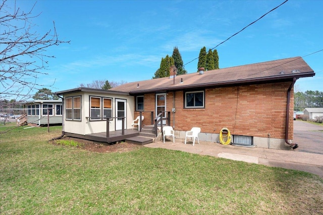 rear view of house with roof with shingles, a yard, a sunroom, and brick siding