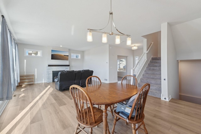 18357 Glacier Way, Lakeville, MN 55044 - dining area featuring a fireplace, light wood finished floors, and stairs