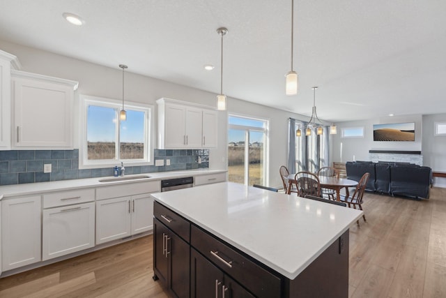 18357 Glacier Way, Lakeville, MN 55044 - kitchen featuring white cabinets, a sink, light countertops, light wood-style flooring, and decorative backsplash