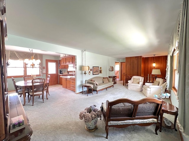 living area with a chandelier, light carpet, and wooden walls