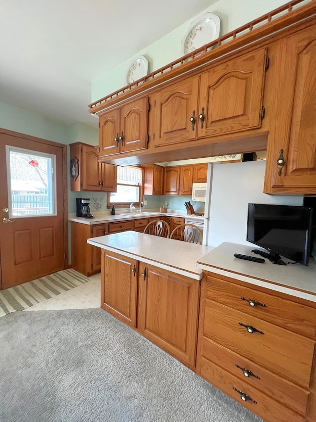 kitchen with brown cabinets, white appliances, and light countertops