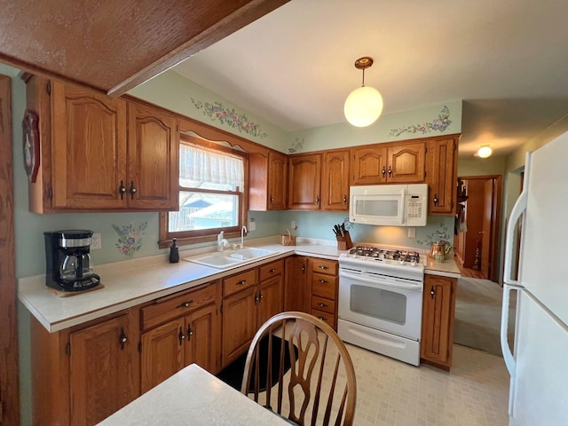 kitchen featuring white appliances, brown cabinetry, a sink, light countertops, and decorative light fixtures
