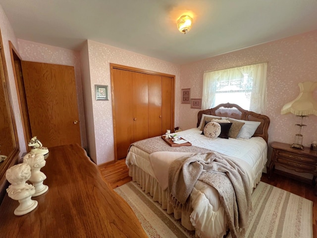 bedroom featuring light wood-style flooring, wallpapered walls, and a closet