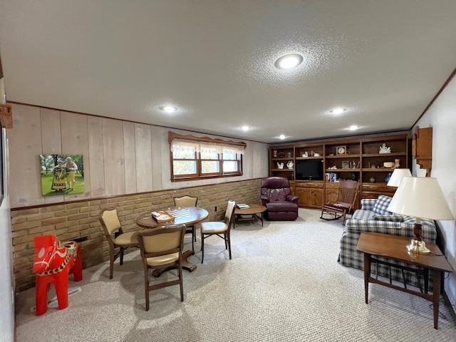 living room featuring carpet, a textured ceiling, wooden walls, and recessed lighting