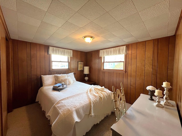 bedroom featuring multiple windows, carpet, and wooden walls