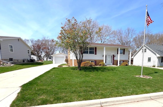raised ranch featuring a detached garage, driveway, a front yard, and brick siding