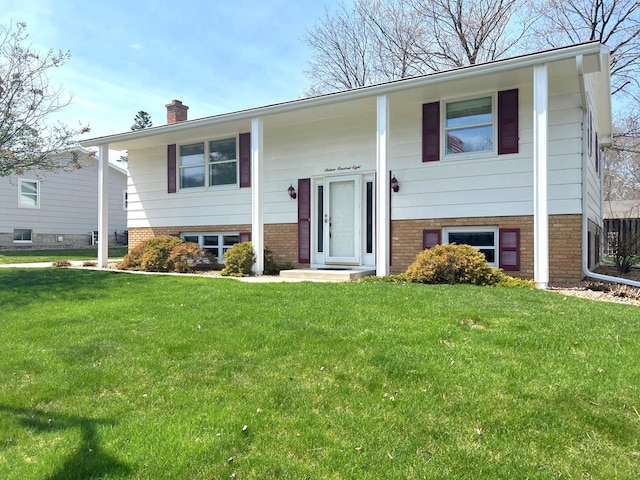 bi-level home with a chimney, a front lawn, and brick siding