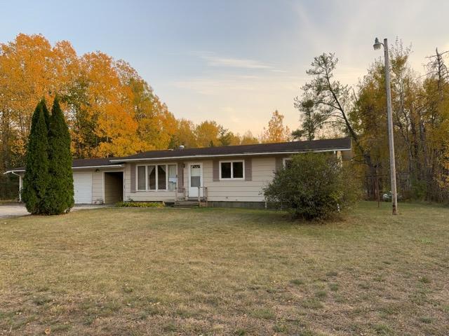 6231 164th St NW, Cass Lake, MN 56633 - back of property at dusk with a garage and a yard