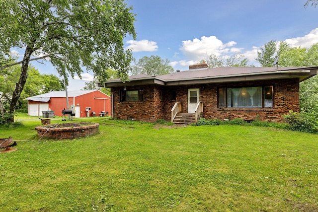 rear view of house with brick siding, an outbuilding, and a yard