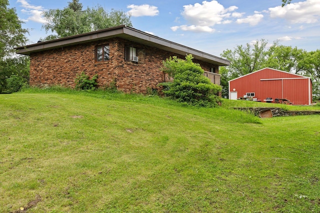 view of home's exterior featuring a yard, brick siding, and an outbuilding