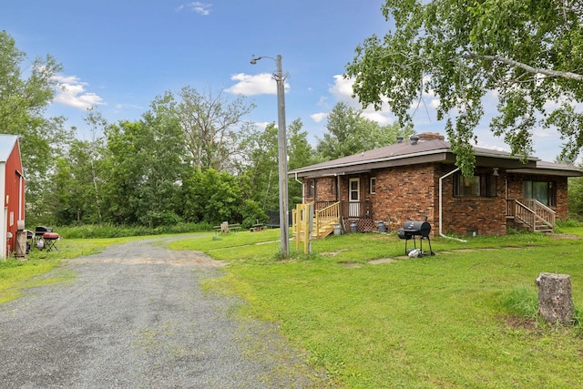 view of home's exterior with a lawn, gravel driveway, and brick siding