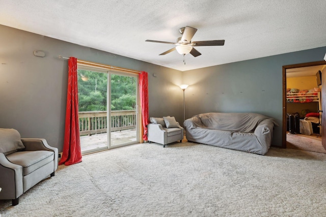 living room featuring ceiling fan, carpet, and a textured ceiling