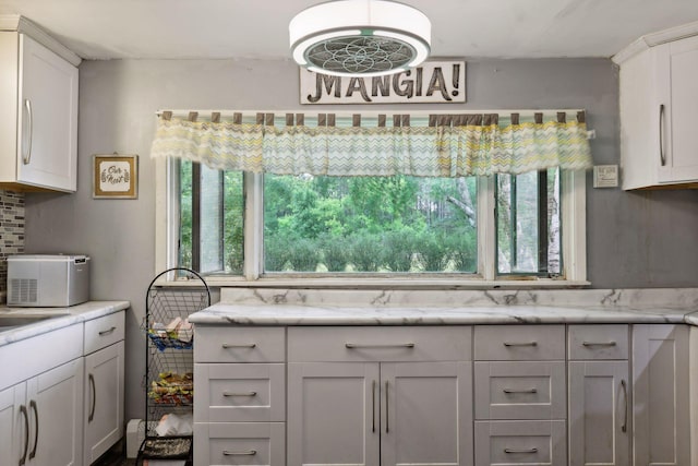 kitchen featuring light stone counters, decorative backsplash, and white cabinetry