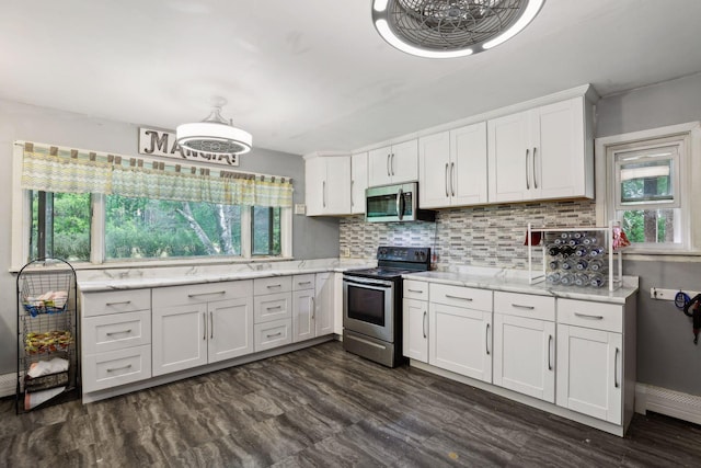kitchen with white cabinets, stainless steel appliances, light stone counters, and tasteful backsplash