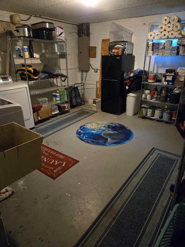unfinished below grade area featuring freestanding refrigerator, washer / clothes dryer, electric panel, and concrete block wall