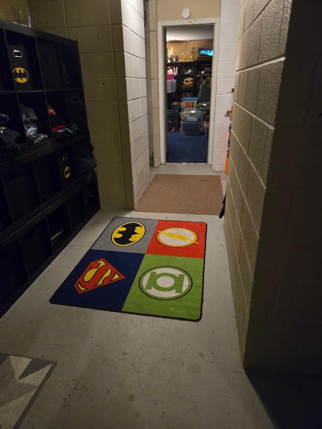 hall featuring concrete block wall and concrete flooring