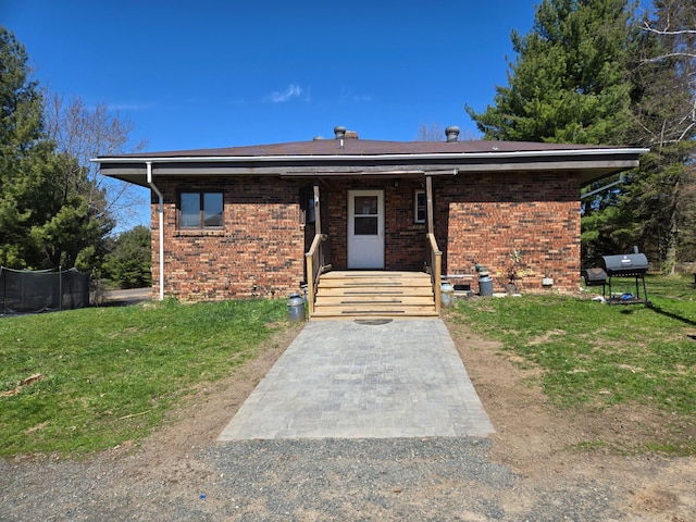 rear view of property featuring brick siding and a yard