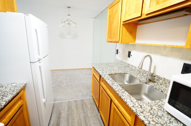 kitchen featuring light carpet, a sink, white appliances, a chandelier, and backsplash