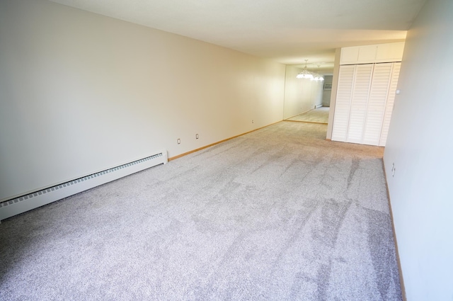 carpeted spare room with baseboards, a notable chandelier, and a baseboard radiator